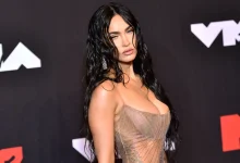 Megan Fox in cropped top & pleated skirt, promoting "Overcompensating" with empowering message.