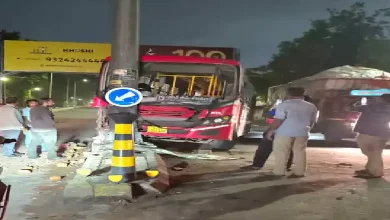 AMTS bus accident in Ahmedabad’s Jamalpur area; vehicle damaged after hitting pole and landing on road divider.