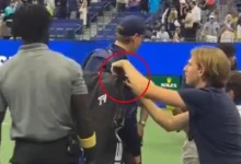 World No. 1 tennis star tries to hand a towel to a fan; another spectator attempts to steal from his kit!