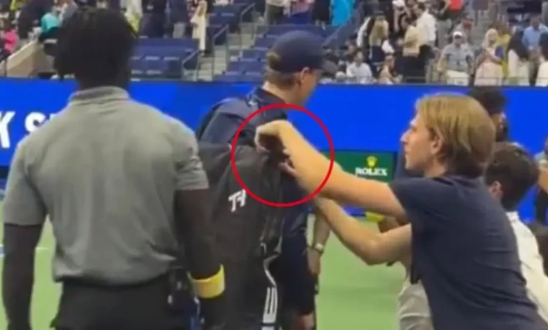 World No. 1 tennis star tries to hand a towel to a fan; another spectator attempts to steal from his kit!